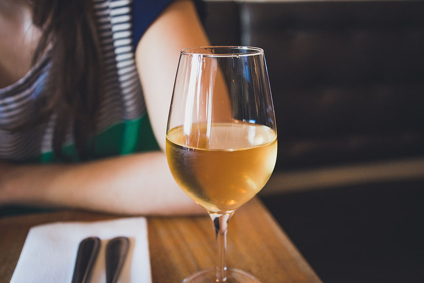 Glass of White Wine on Wooden Table in Restaurant