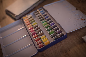 Open watercolor paint set on wooden table