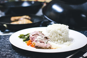 Plated duck breast with rice and vegetables in kitchen