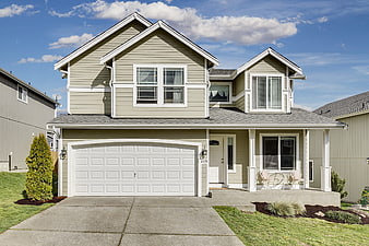 Modern beige suburban house with white garage and blue sky