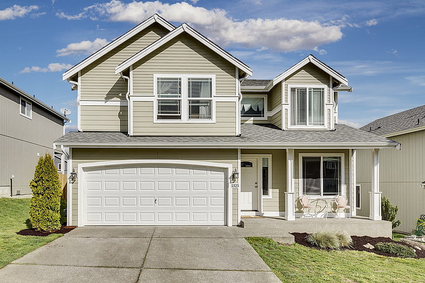 Modern beige suburban house with white garage and blue sky