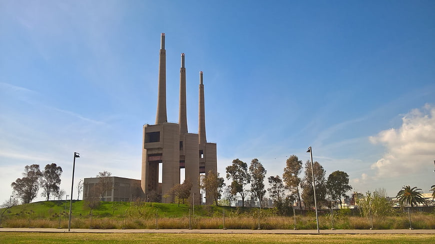 Three tall industrial chimneys against a blue sky