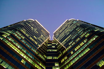 Symmetrical low angle view of modern glass skyscrapers at dusk