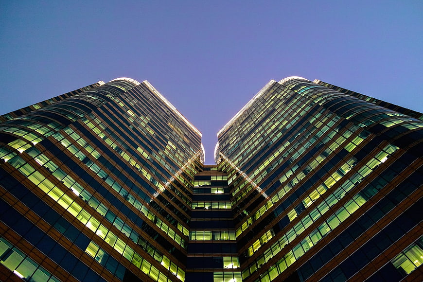 Symmetrical low angle view of modern glass skyscrapers at dusk