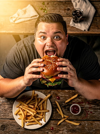 Man Eating Giant Burger with Fries Overhead View