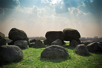 Ancient megalithic stones in a grassy field with sun rays