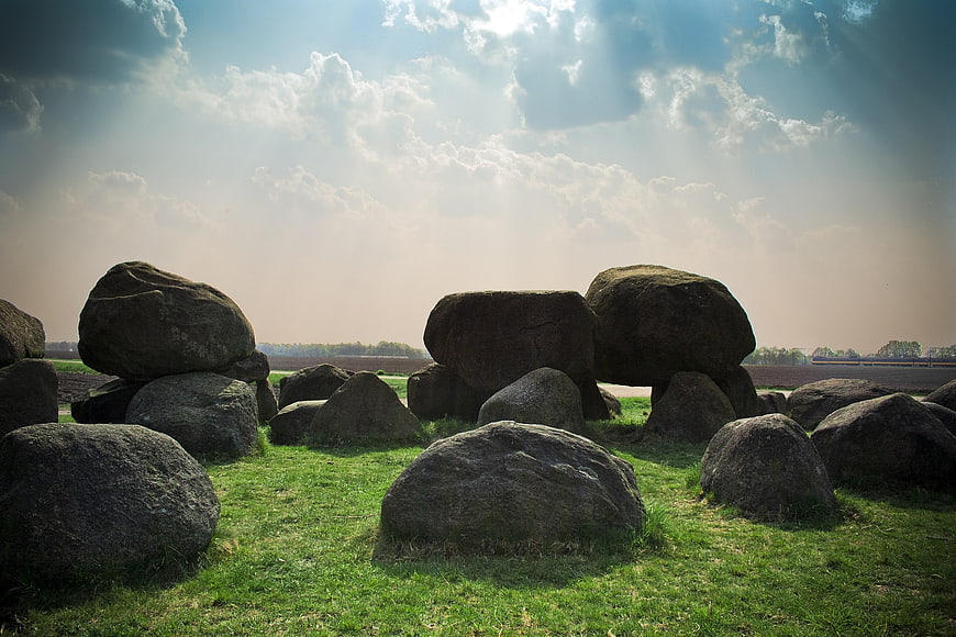Ancient megalithic stones in a grassy field with sun rays