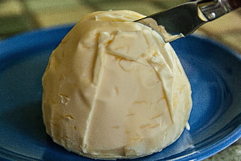 Close-up of a block of butter on a blue plate with a knife