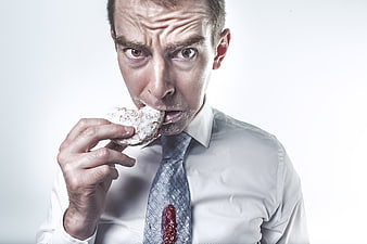 Messy businessman eating donut with powdered sugar and jam stain