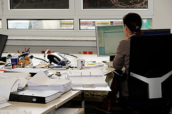 Woman Working At Cluttered Office Desk With Computer Monitor