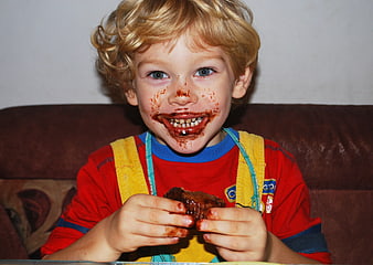 Happy child eating chocolate muffin with messy face