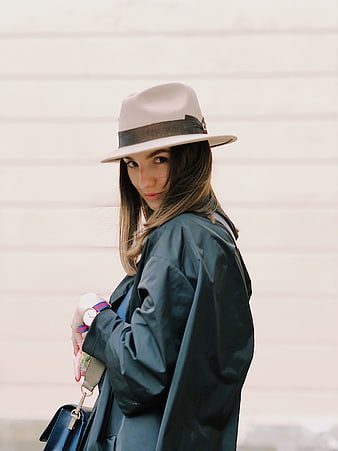 Stylish woman in hat and coat looking back