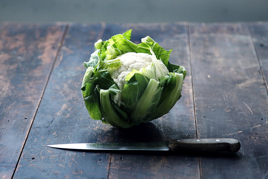Fresh Cauliflower Head With Kitchen Knife On Rustic Dark Wooden Table