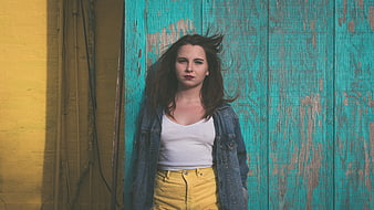 Young woman in denim jacket against colorful textured wall
