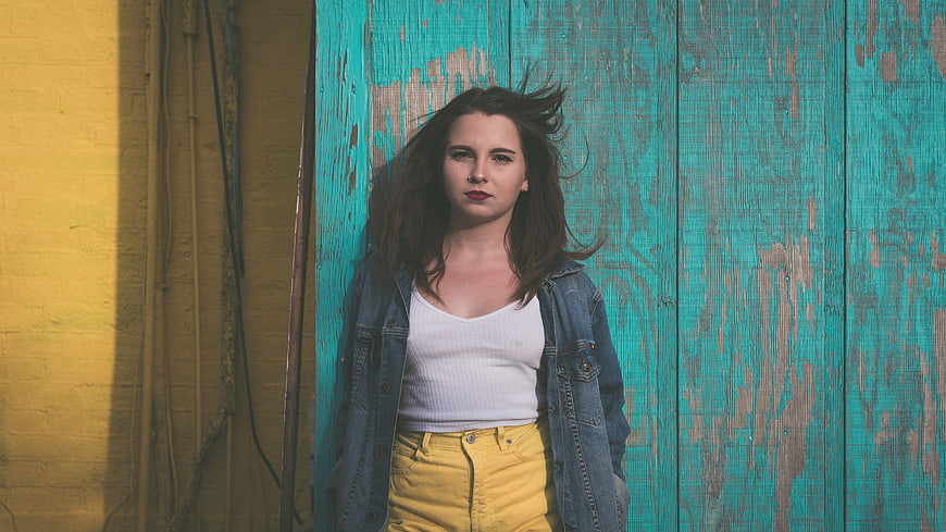 Young woman in denim jacket against colorful textured wall