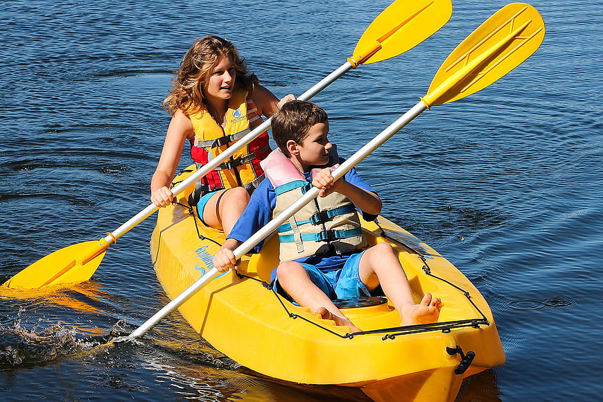Woman and Boy Paddling Yellow Kayak on Blue Water