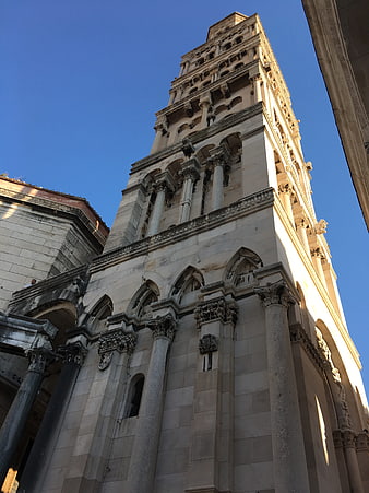 Low angle view of historic stone church tower against blue sky