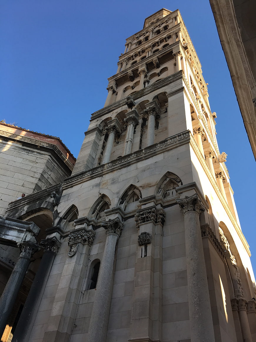 Low angle view of historic stone church tower against blue sky