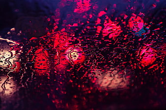 Abstract red and blue neon lights through raindrops on glass