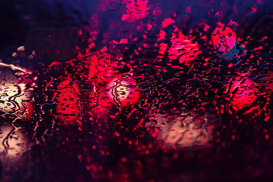 Abstract red and blue neon lights through raindrops on glass