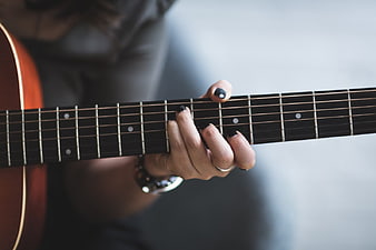 Close-up of woman playing acoustic guitar with black nail polish