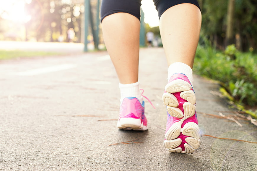 Close-up of woman's legs in pink running shoes on outdoor path