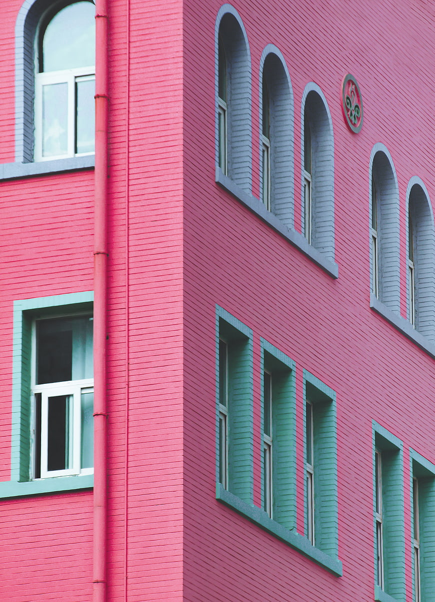 Colorful pink and teal brick building facade with arched windows