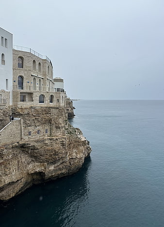 Coastal stone architecture on rocky Mediterranean cliff overlooking calm ocean