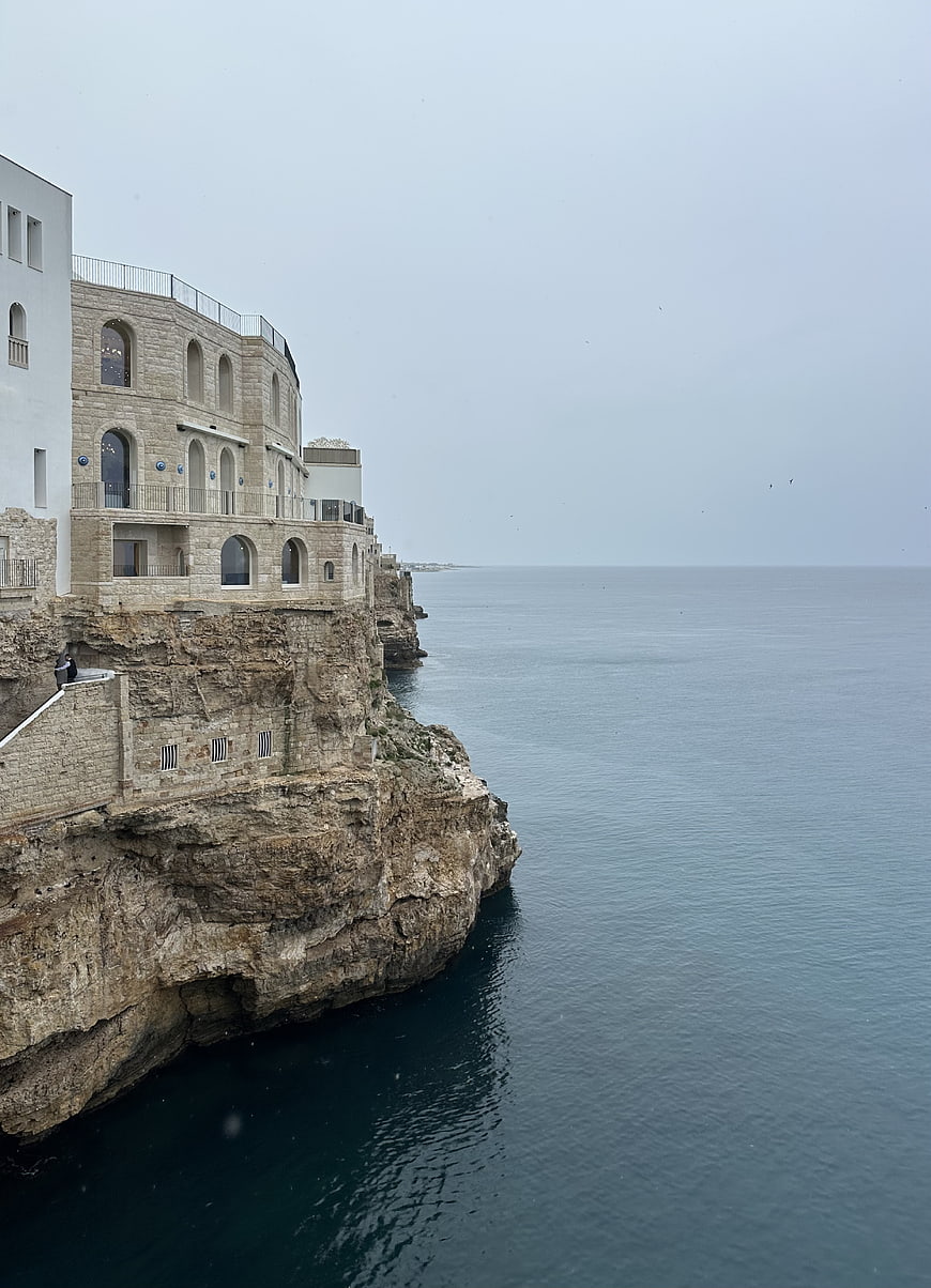 Coastal stone architecture on rocky Mediterranean cliff overlooking calm ocean