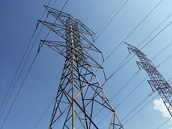 Low angle view of high voltage power transmission towers against blue sky