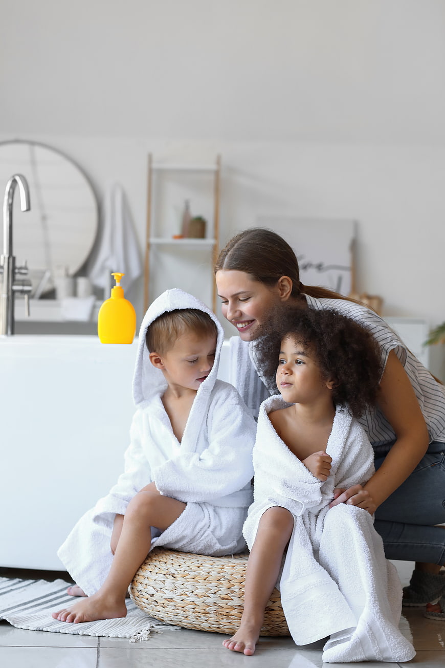 Mother with Two Children in Bathrobes in Bright Bathroom
