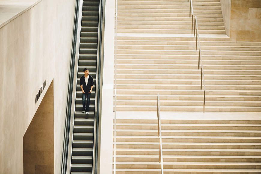 Man on Escalator in Modern Minimalist Architecture
