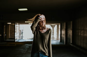 Woman with hand on head in dim parking garage
