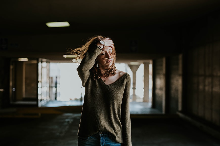 Woman with hand on head in dim parking garage