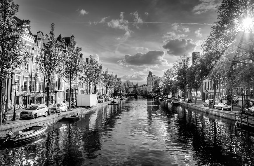 Black and white Amsterdam canal with historic architecture and boats