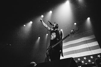 Rock musician singing on stage with bass guitar and flag