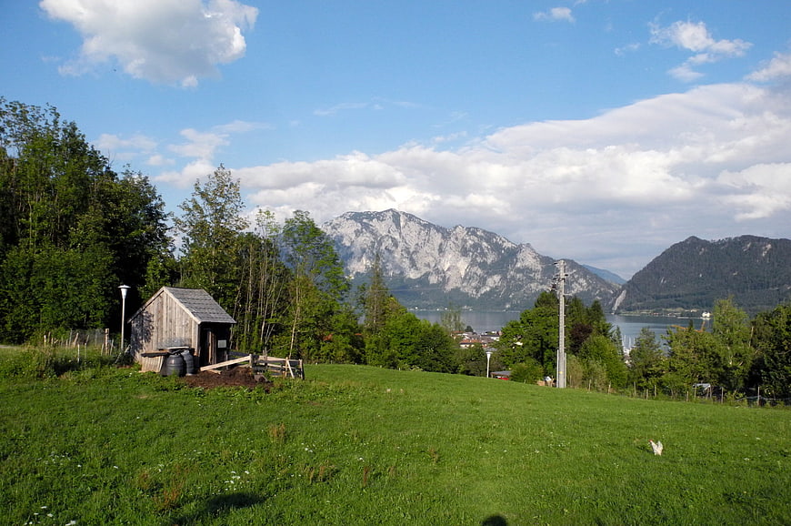 Rustic wooden shed on green hill with mountain lake view