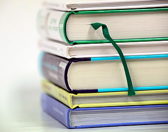 Stack of colorful hardcover books with green ribbon bookmark