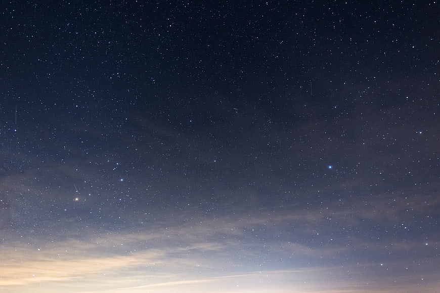 Starry Night Sky with Faint Horizon Glow and Wispy Clouds