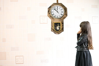 Girl in leather jacket looking at vintage wall clock