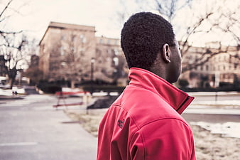 Man in Red Jacket Standing in Urban Park