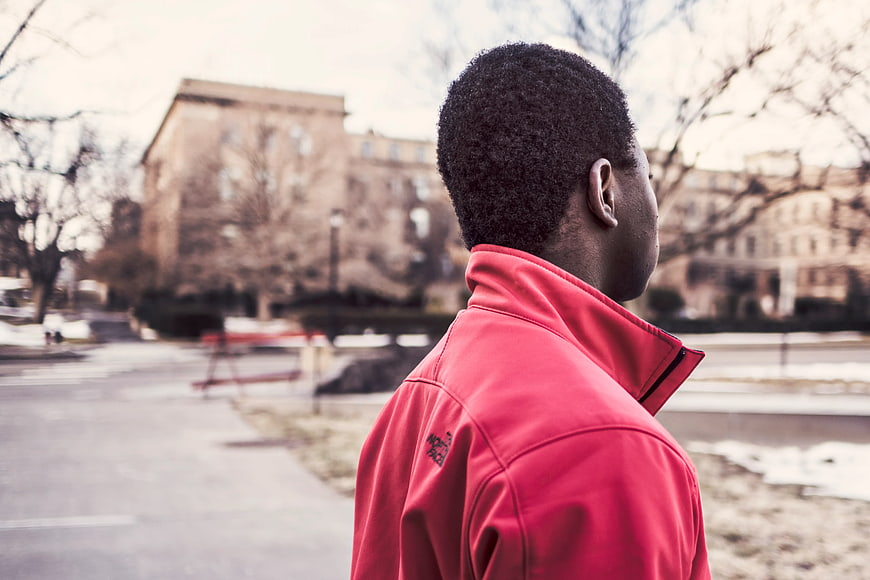 Man in Red Jacket Standing in Urban Park