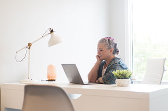 Senior woman working on laptop at bright home office desk
