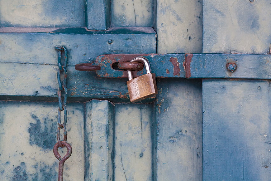 Rusty Padlock on Weathered Blue Wooden Door