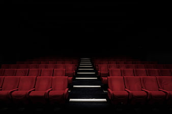 Empty red cinema seats in dark theater auditorium