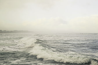 Foggy ocean waves crashing on a misty overcast day