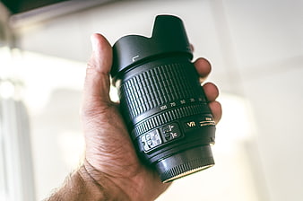 Hand holding professional camera lens with hood