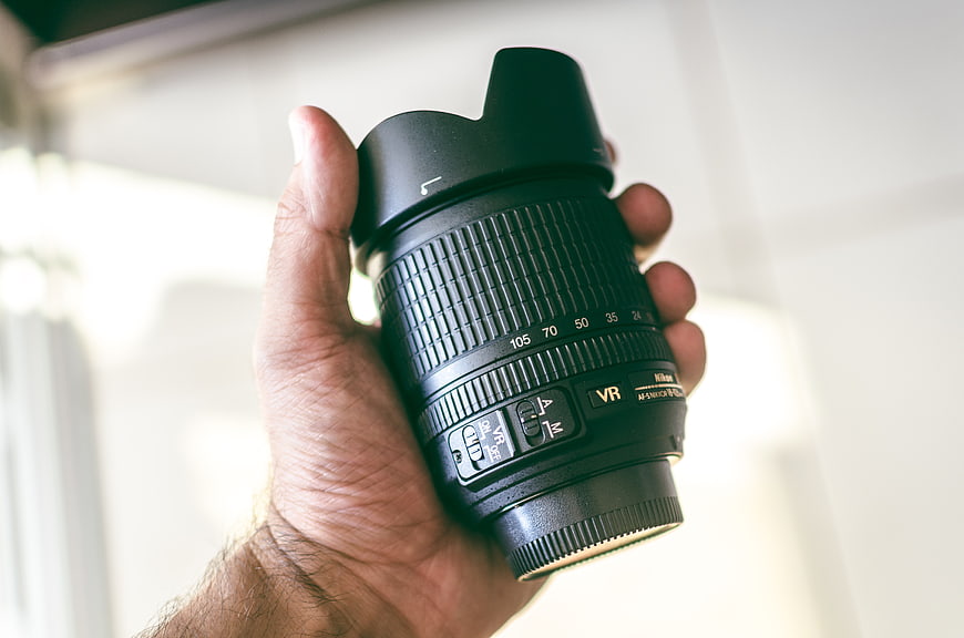 Hand holding professional camera lens with hood