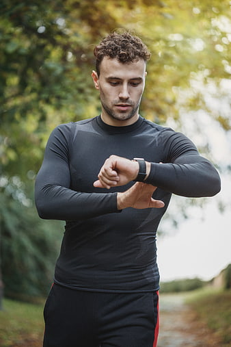 Athletic man checking smartwatch while running outdoors