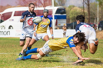 Rugby players tackling and passing ball on grass field